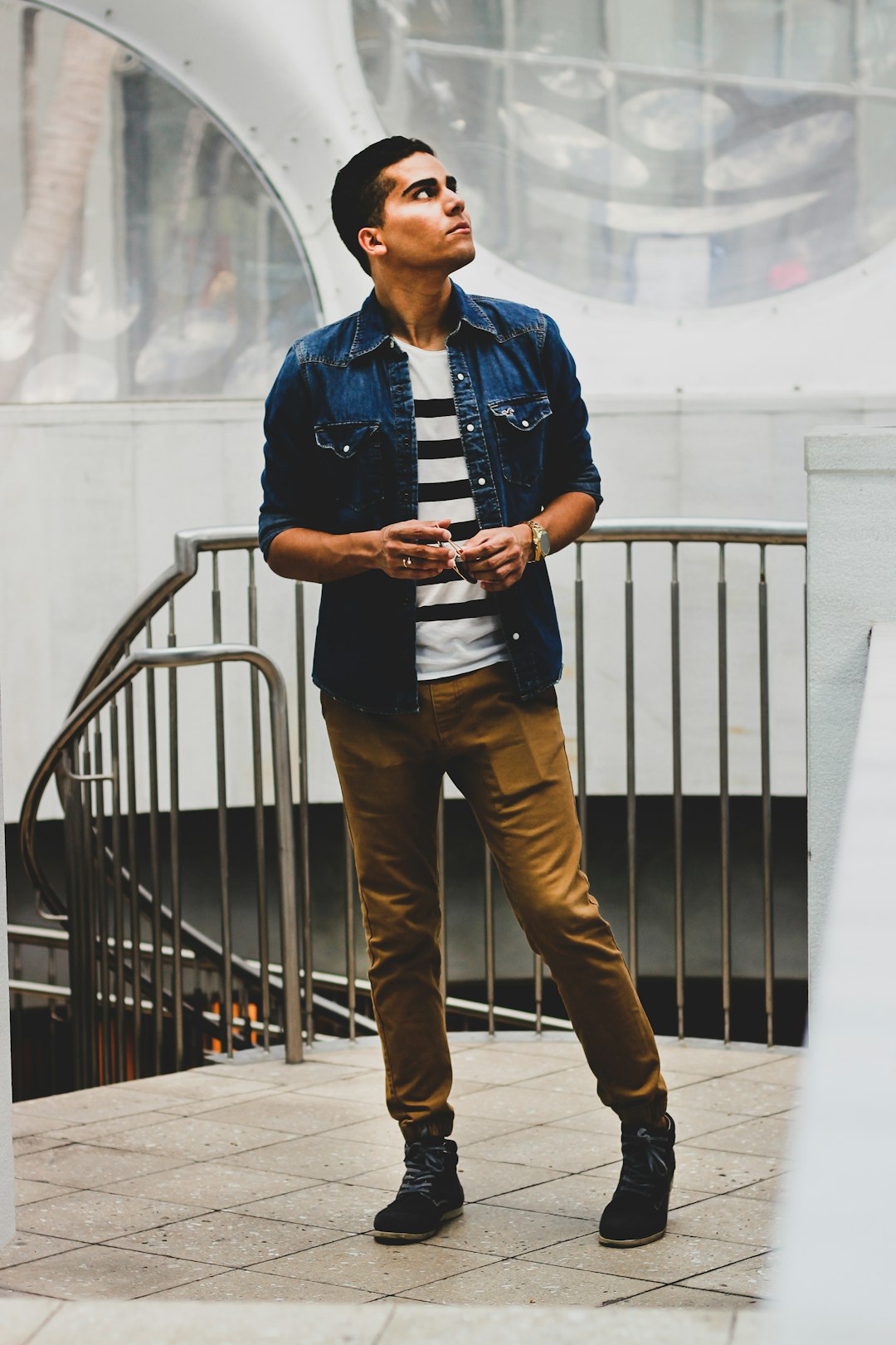 man standing beside stairway rail during daytime