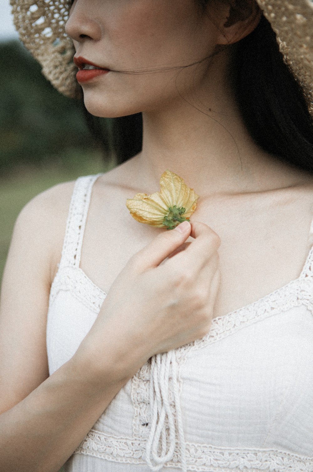 Femme portant un haut blanc sans manches tenant une fleur marron