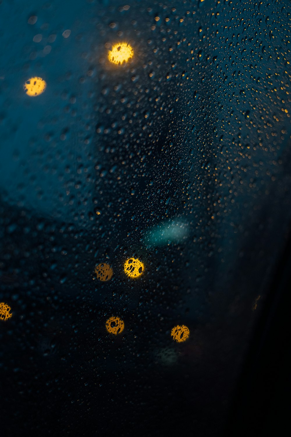 노란 불빛이 있는 창문에 빗방울이 떨어진다
