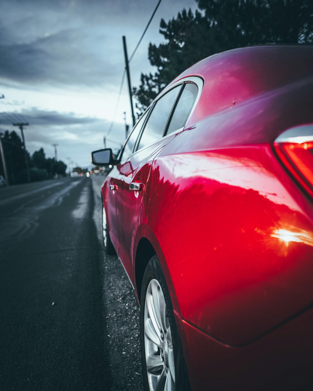 red sedan on road near utility pole