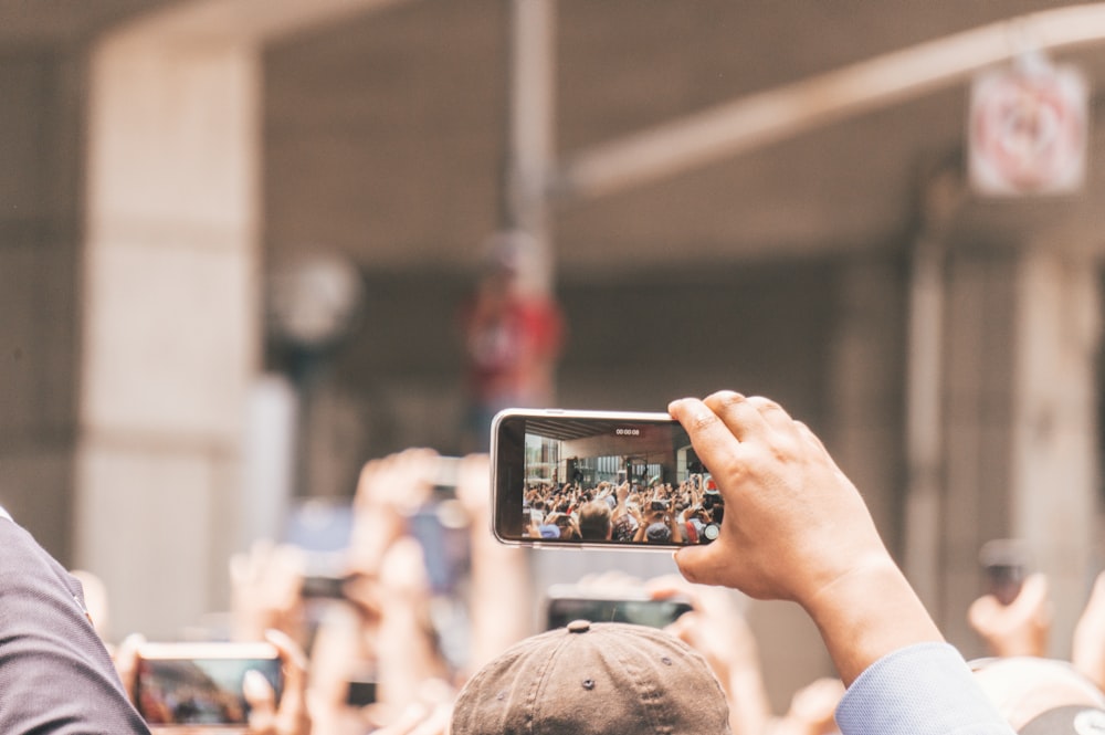 selective focus photography of person holding smartphone taking video
