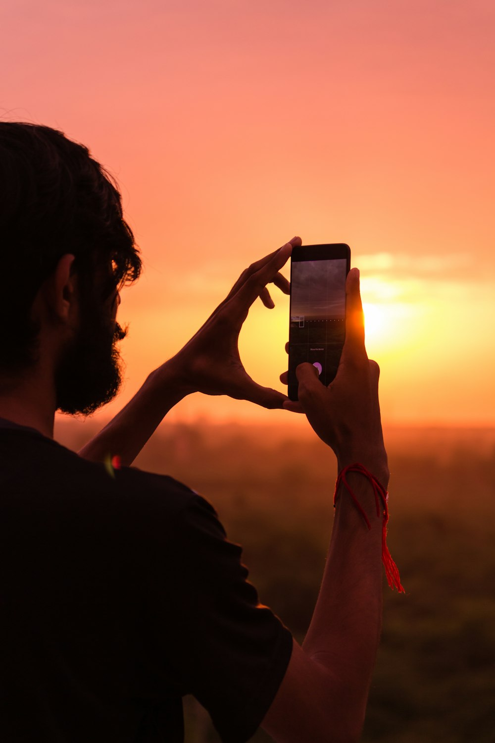 man holding smartphone on high ground during golden hour