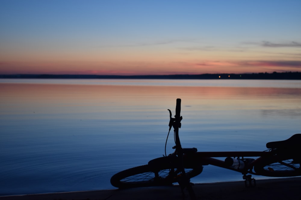 lying bike near a body of water during goldne hour
