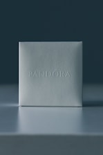 Close-up of a sleek black matte jewelry box with a minimalist silver logo on top.