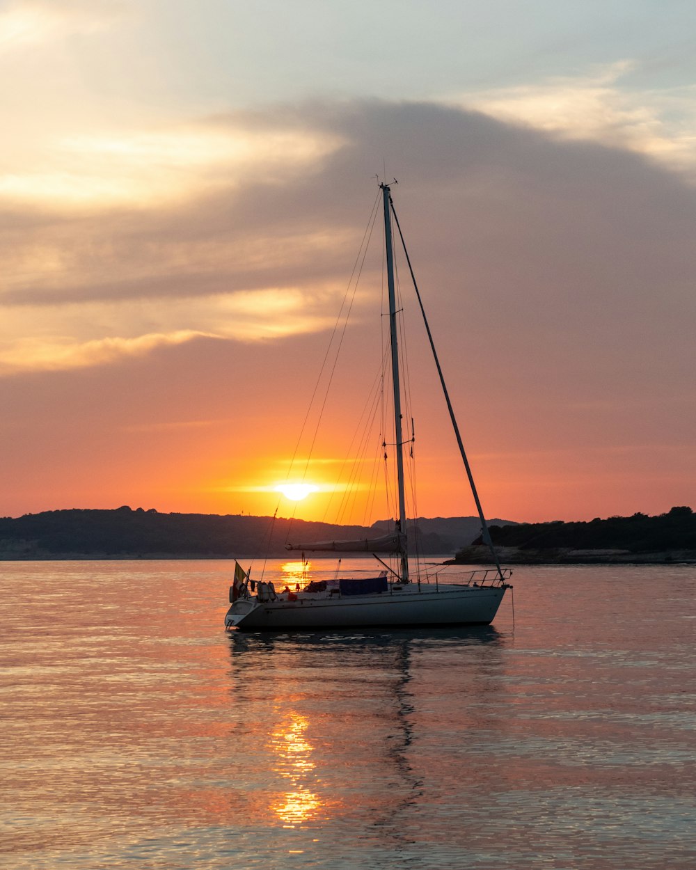 white sail boat on body of water during sunset