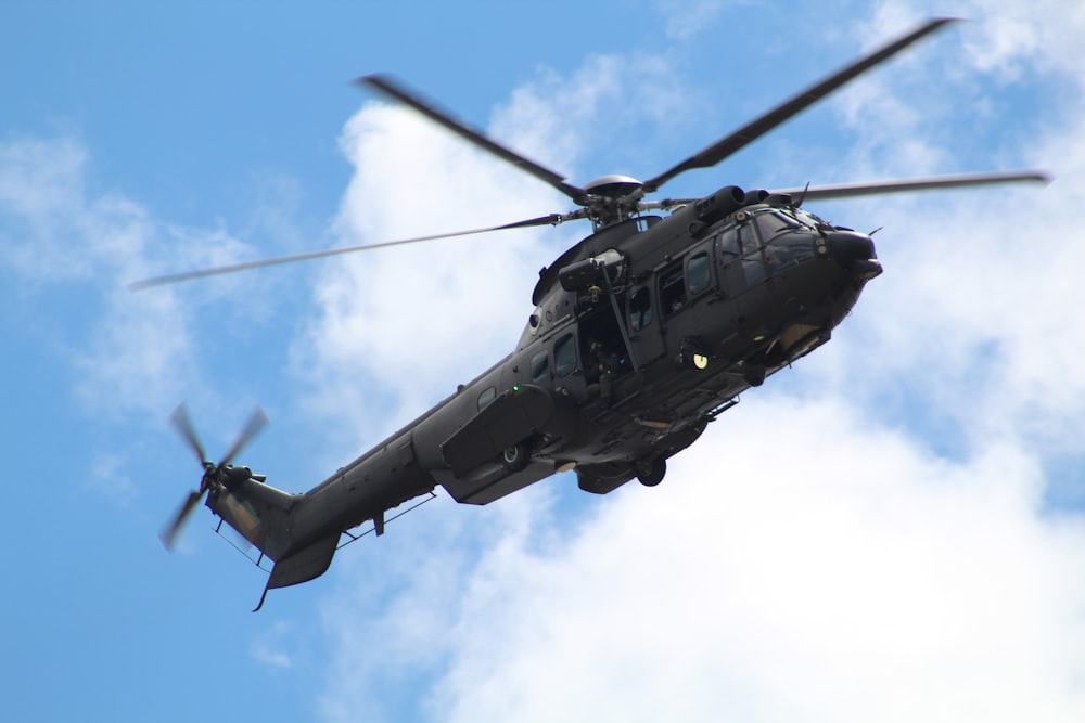 black helicopter under white clouds