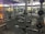 A well-equipped gym with various weightlifting equipment including benches, barbells, dumbbells, and weight racks. There are mirrors on the walls and rubber flooring. The lighting is bright yet soft, and the gym appears clean and organized.