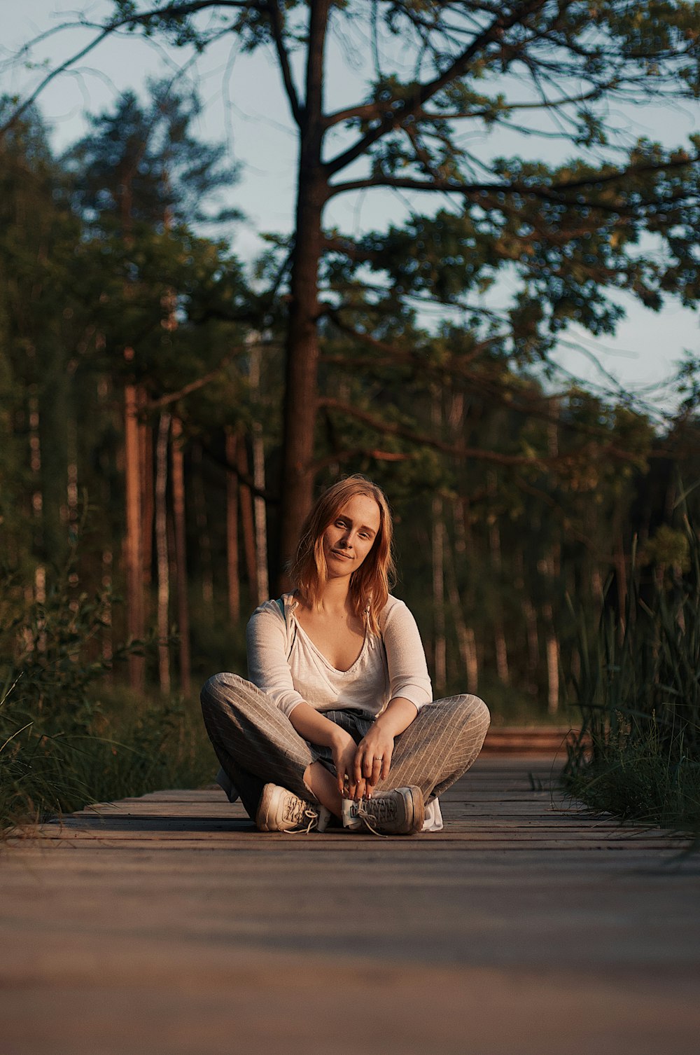 woman sitting on pathway near tree during daytime