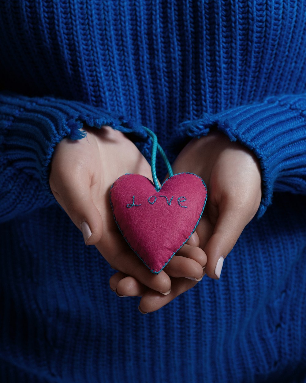 personne tenant un coussin rouge en forme de coeur