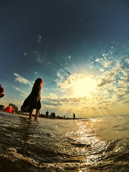 A sunlit beach scene in California with a teenage girl smiling and journaling by the shore.
