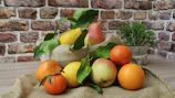 Close-up of fresh local fruits arranged on rustic wooden table with green leaves.