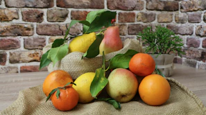 Close-up of fresh local fruits arranged on rustic wooden table with green leaves.