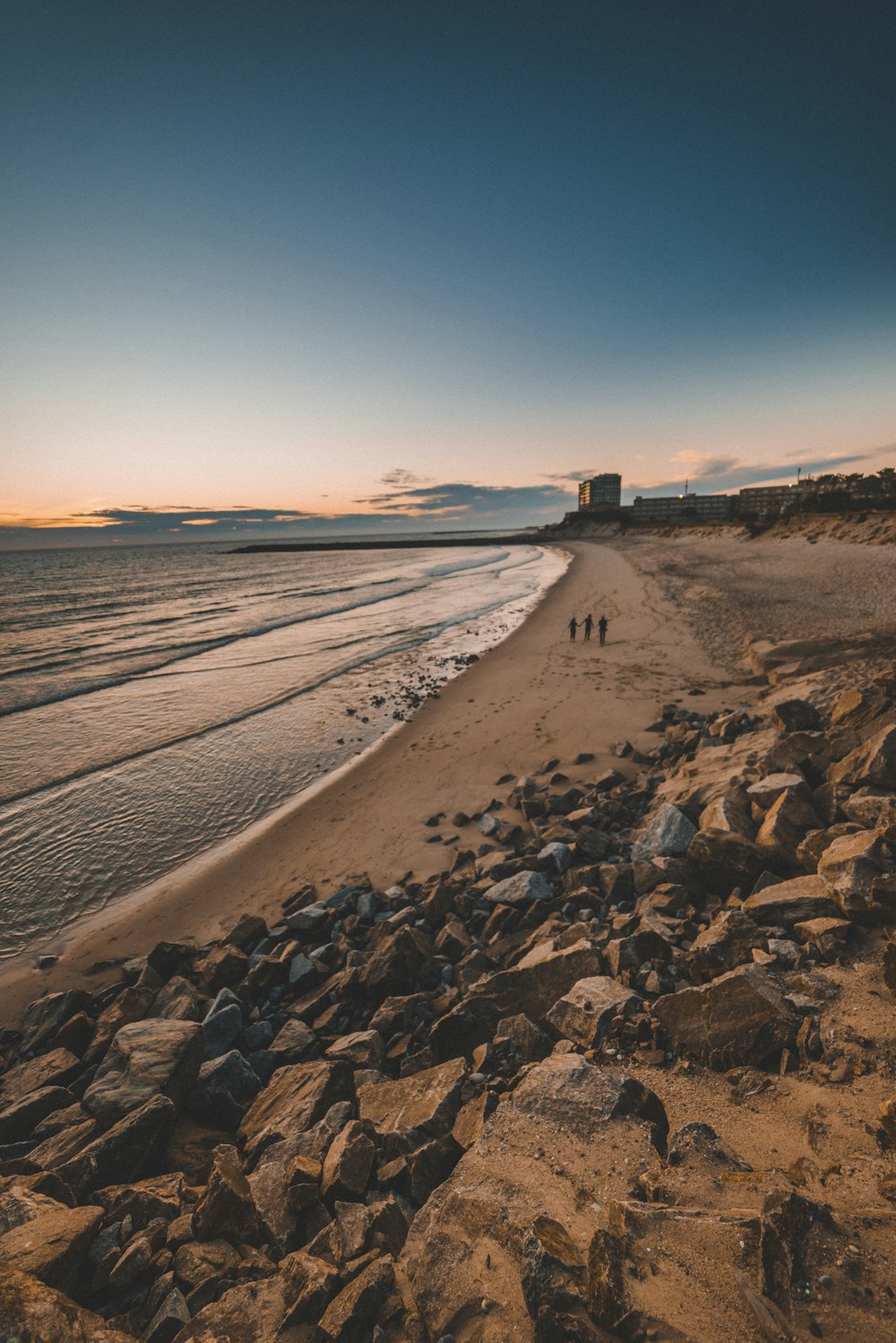 three persons walking beside beach line