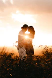 man and woman standing and touching foreheads during golden hour