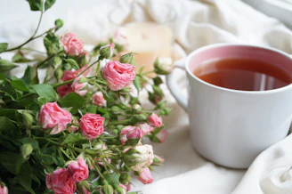 A rustic ceramic mug filled with steaming tea, placed beside dried flowers.
