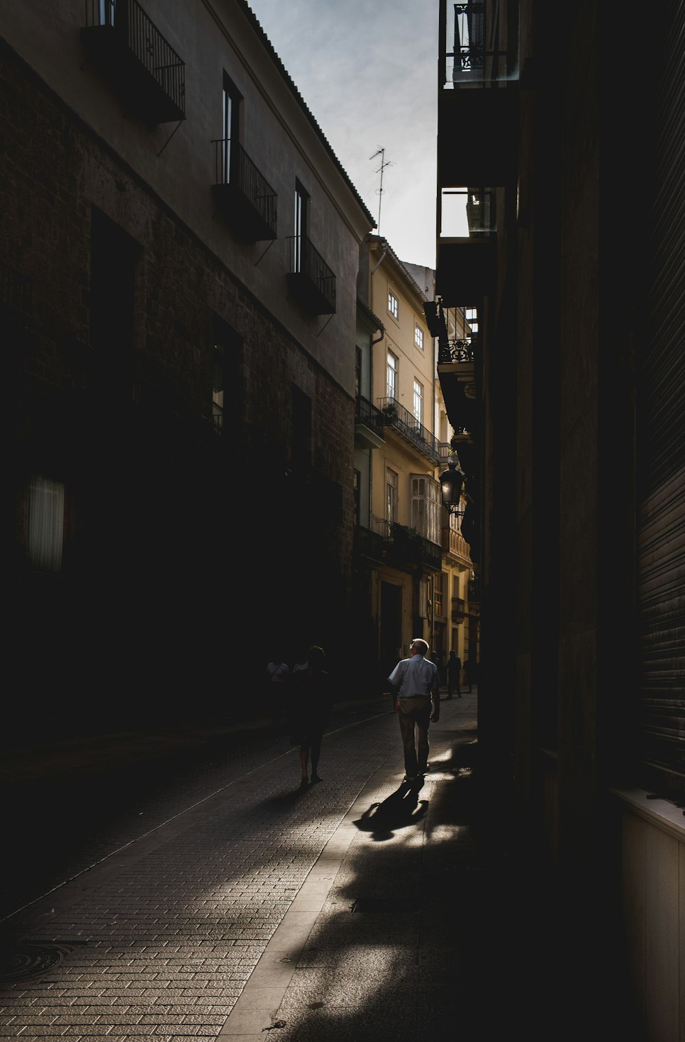 man wearing white shirt walking beside building