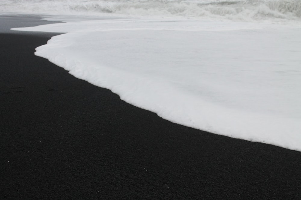 une plage de sable noir avec des vagues qui arrivent