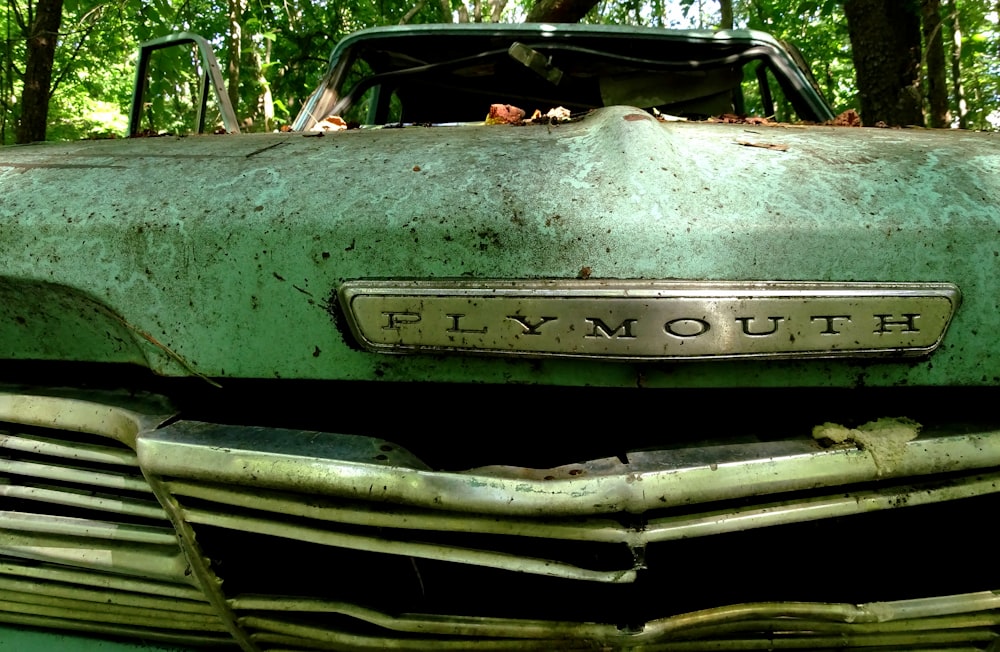 classic green Plymouth car near trees