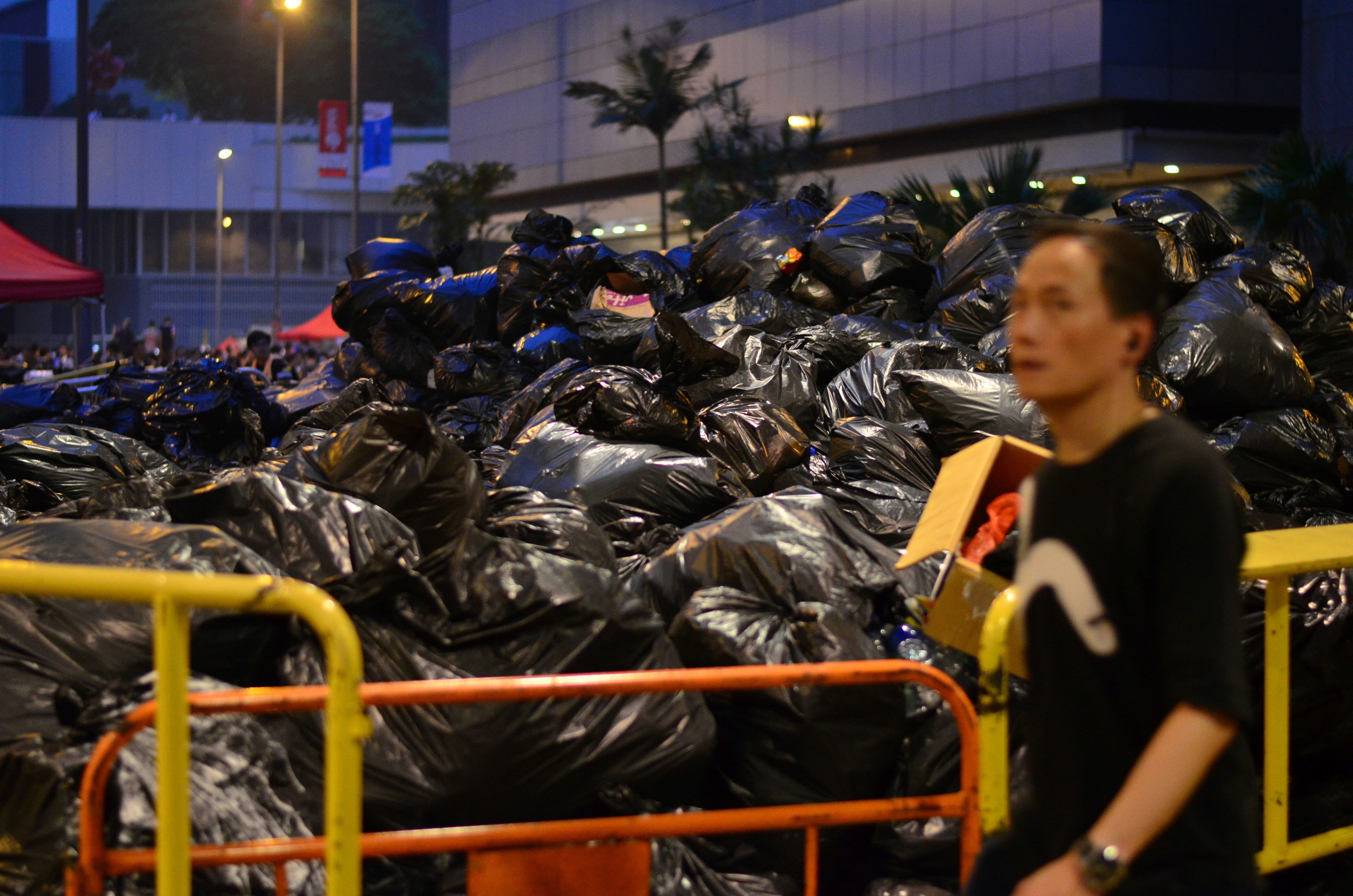 man in black shirt standing beside garbages