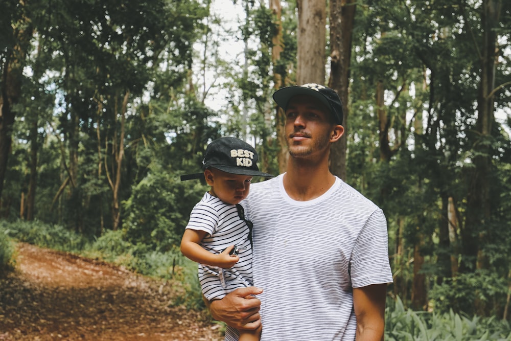 man carrying child inside forest