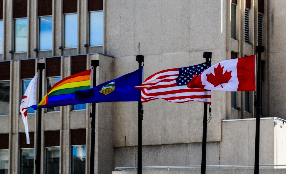 several country flags hoisted in front of grey building