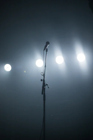 A dimly lit stage with a single spotlight illuminating a vintage microphone, evoking intimate performances.