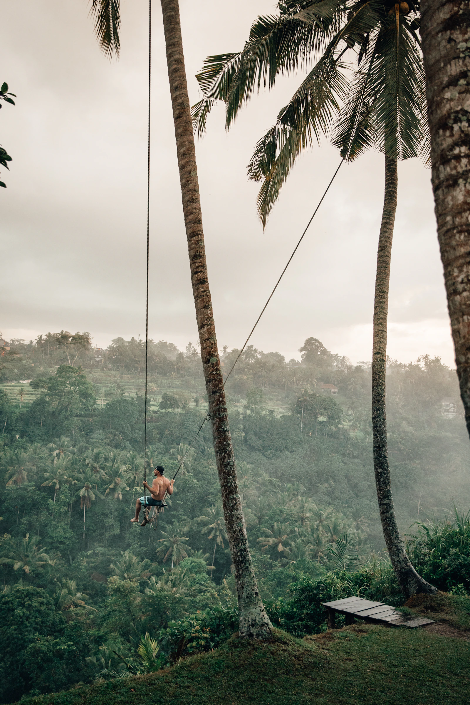 Un viajero en un columpio sobre la selva de Bali entre la niebla