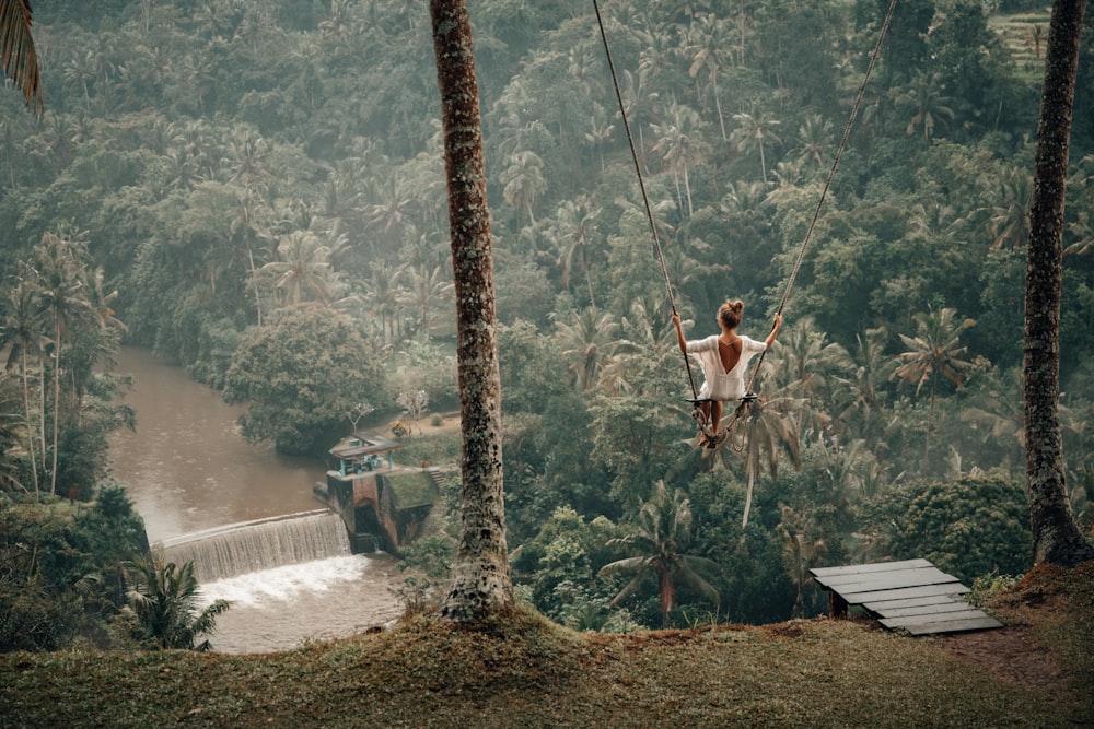 woman wearing white top on swing across river