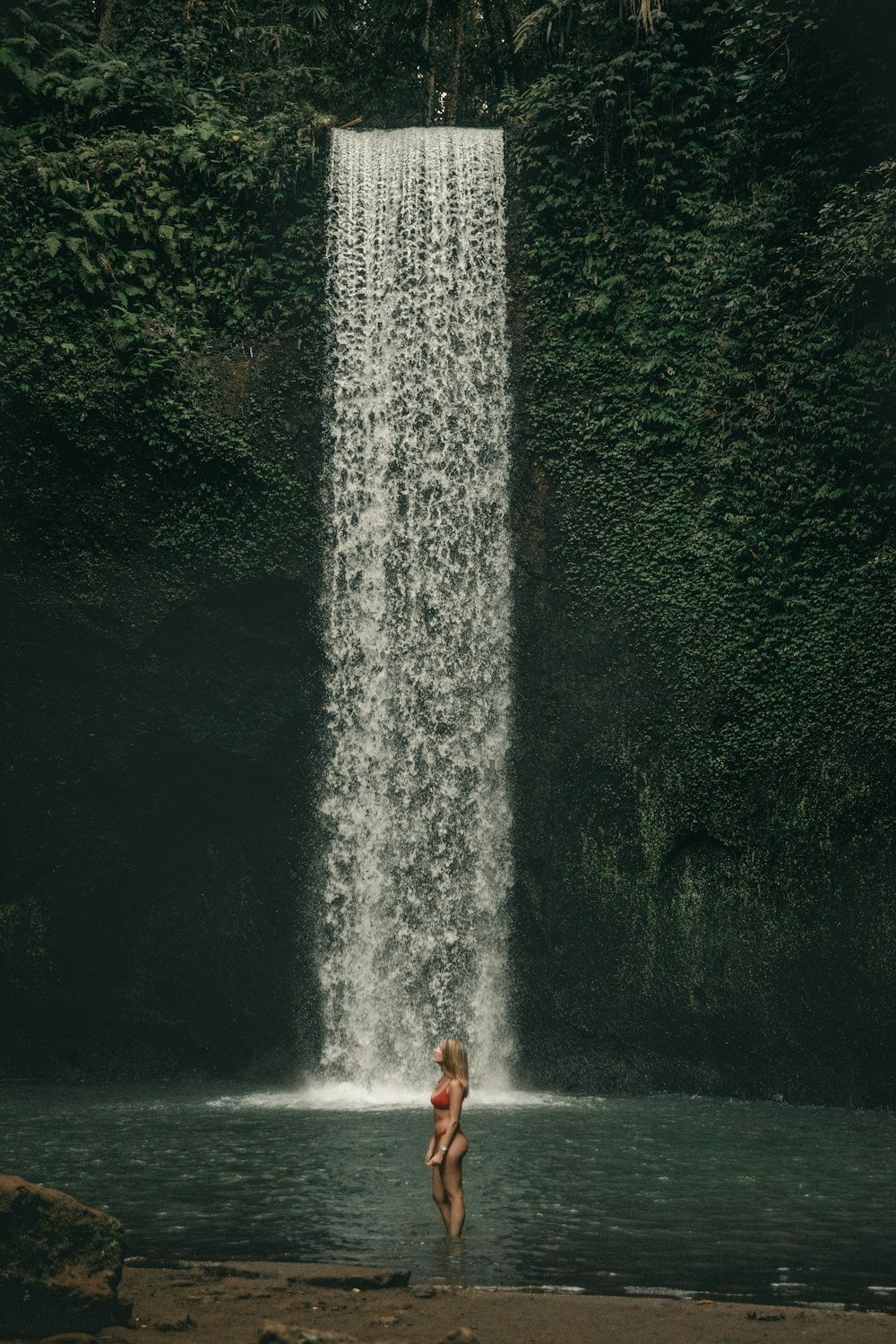 Frau, die tagsüber in der Nähe des Wasserfalls steht