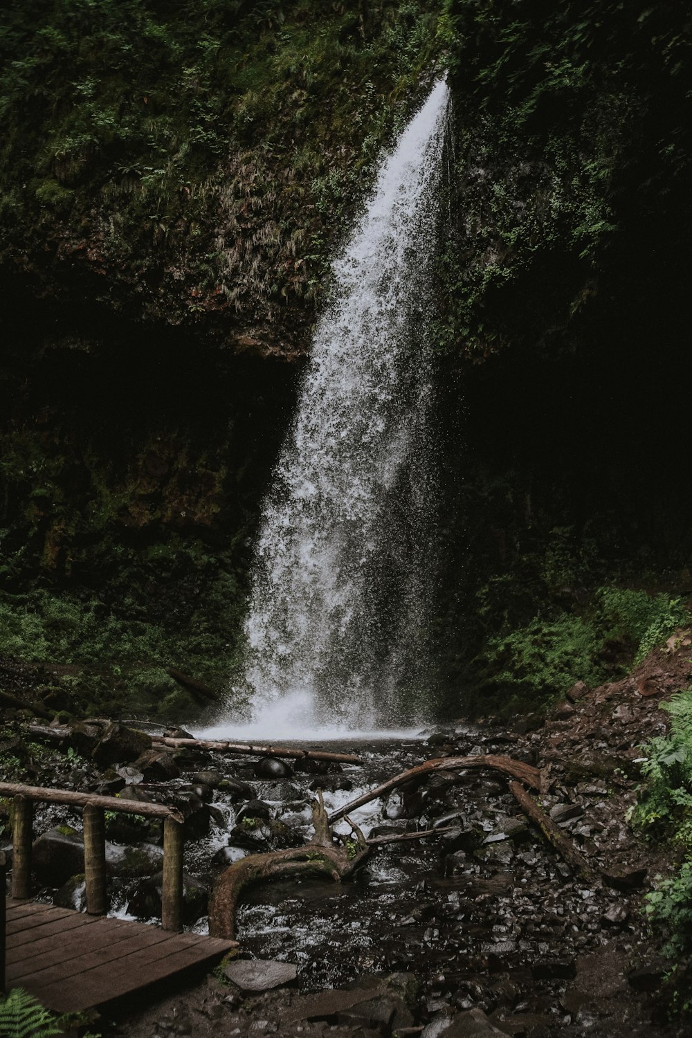 brown wooden walk bridge in front of waterfalls