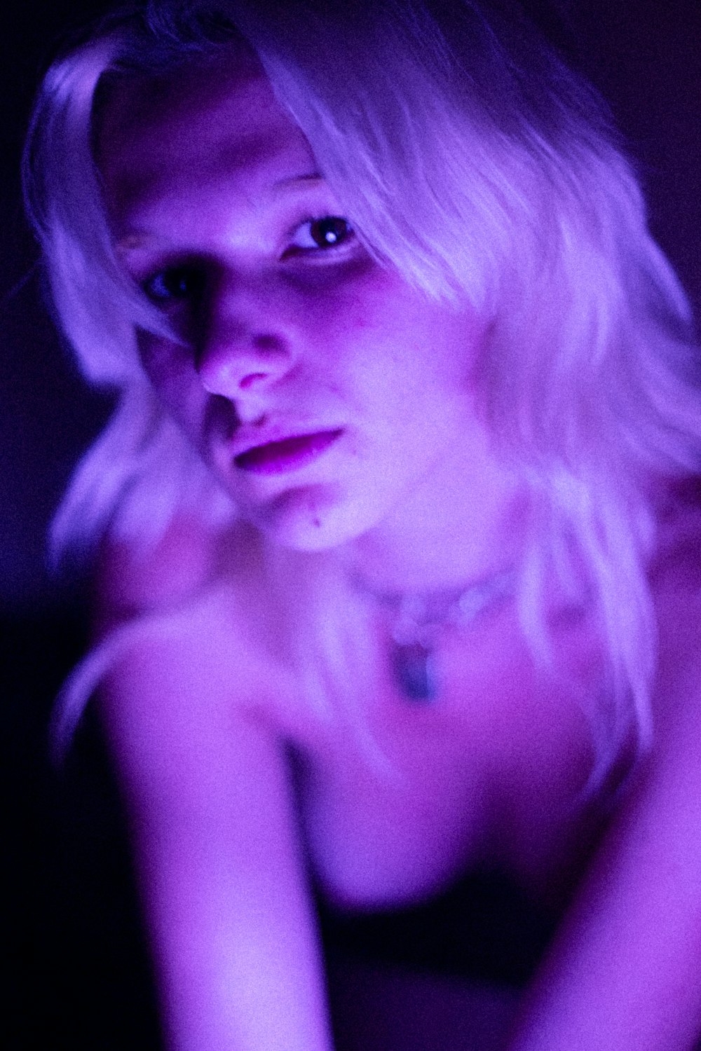 woman wearing silver-color necklace inside dark surface