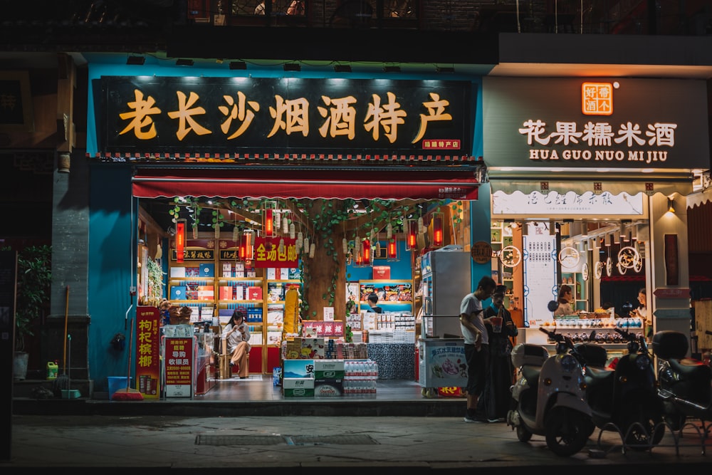 man in white shirt stands in front of stores near scooters