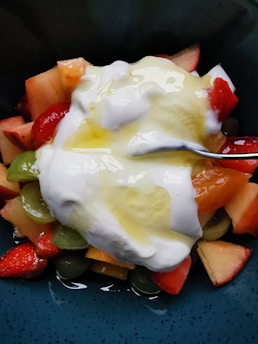 A vibrant bowl of mixed fresh fruits with a drizzle of honey on top.