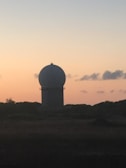Close-up of advanced radar equipment scanning the horizon at dusk.
