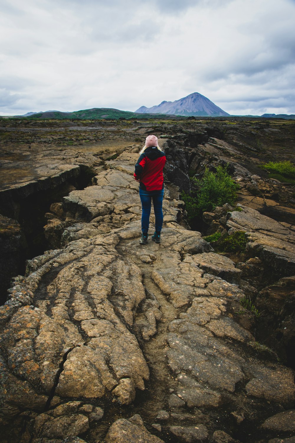 person in red long-sleeved shirt standing on cliff