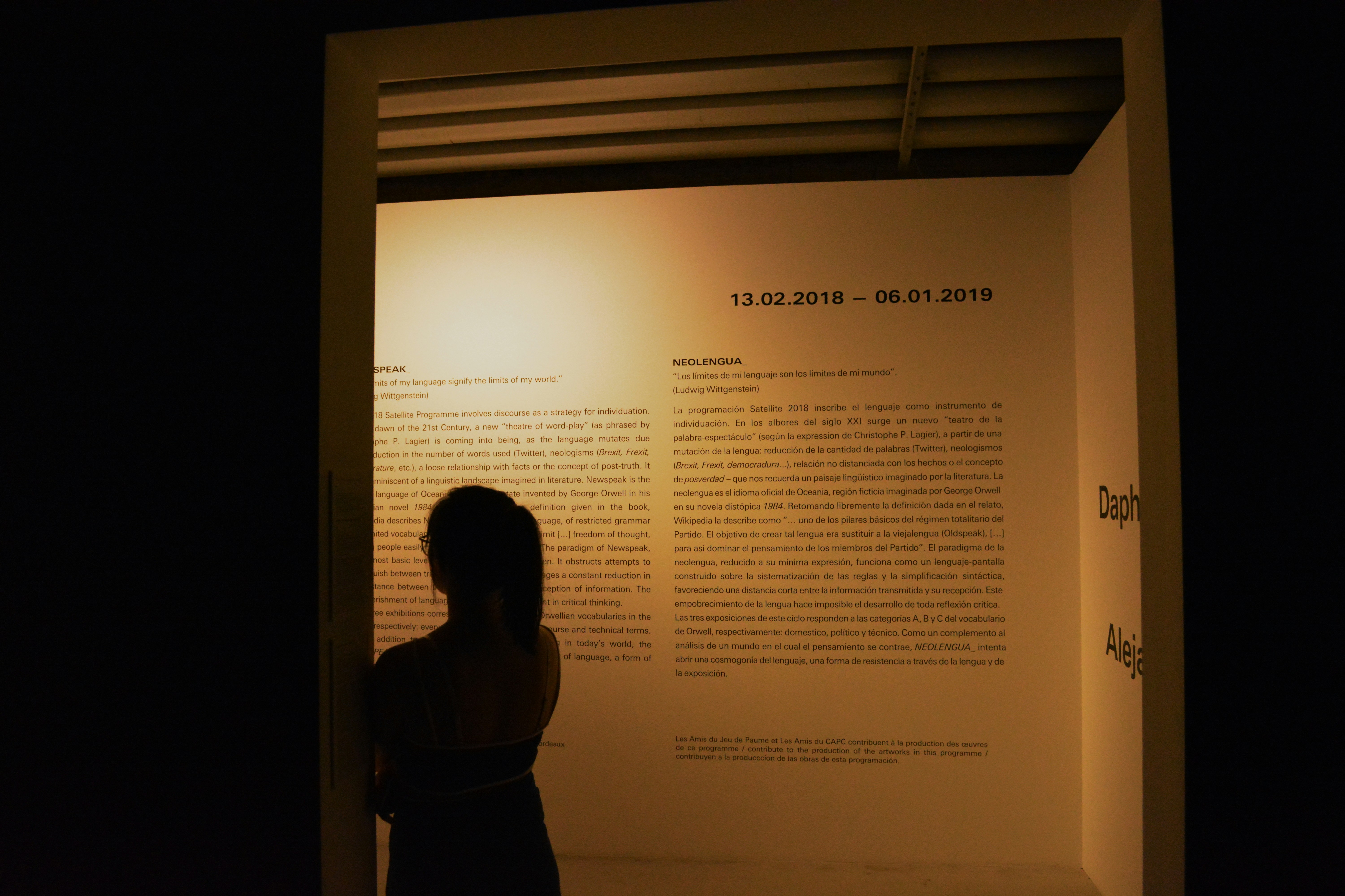 woman leaning beside white printed wall