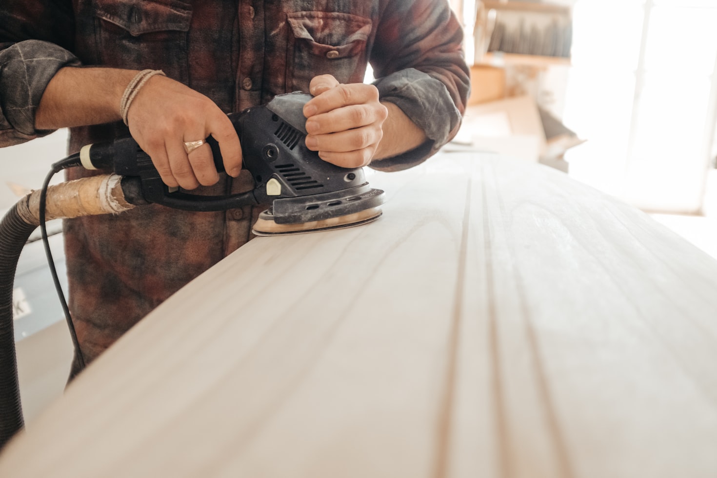 A person using a circular sander on a piece of wood.