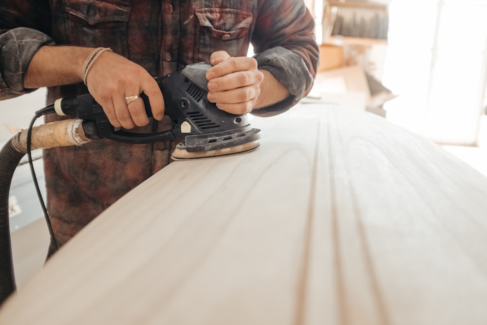 man using sander on beige wooden surface
