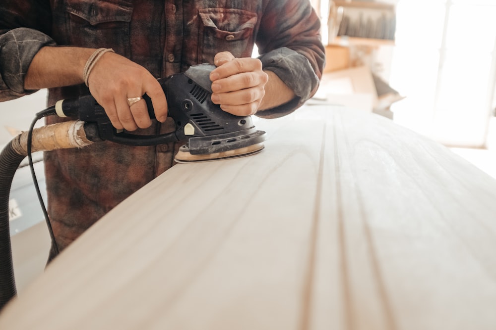 Hombre usando lijadora sobre superficie de madera beige