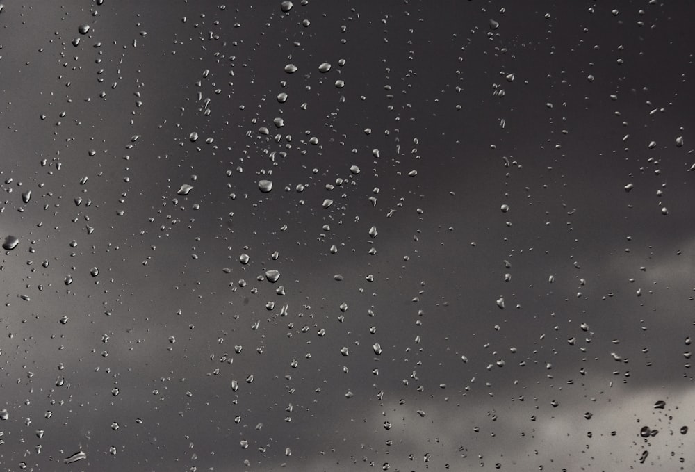 rain drops on a window with a cloudy sky in the background