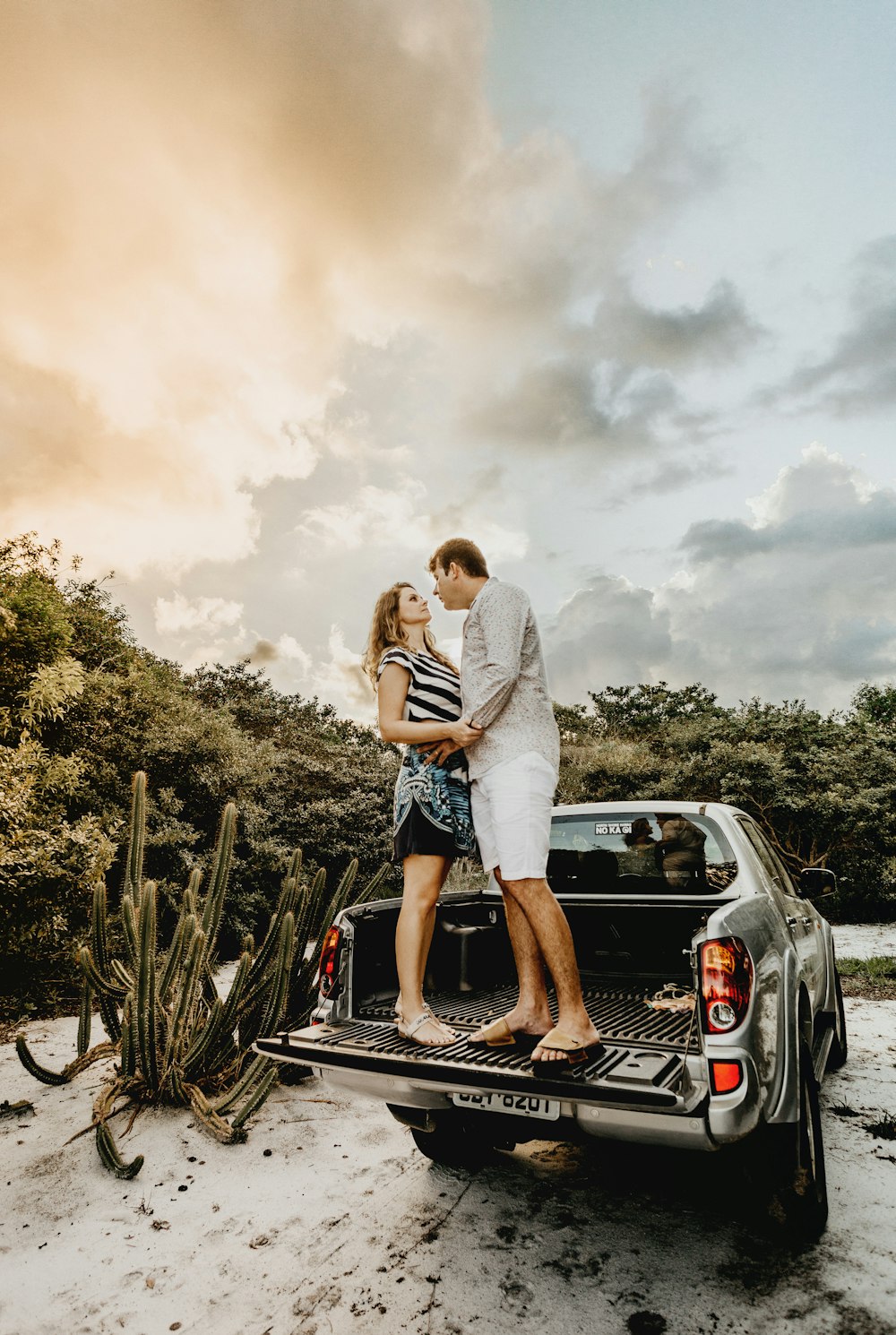 couple standing on truck bed during golden hour
