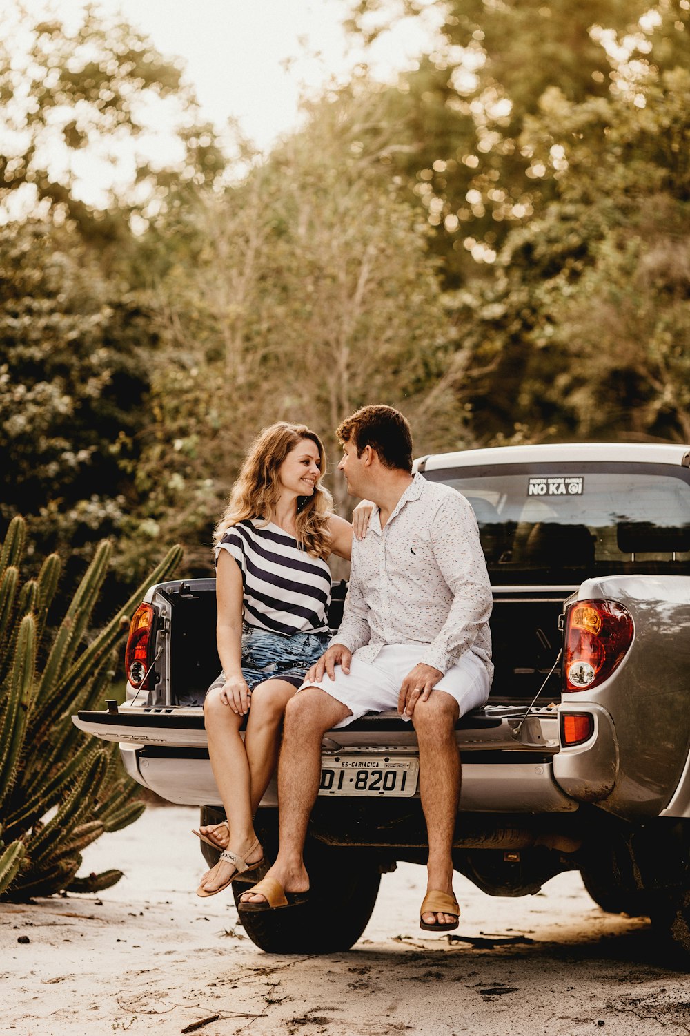 man and woman sitting on pickup truck's trailgate