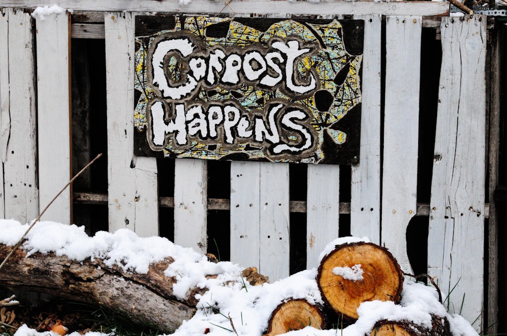 snow covered log beside wooden wall with sign