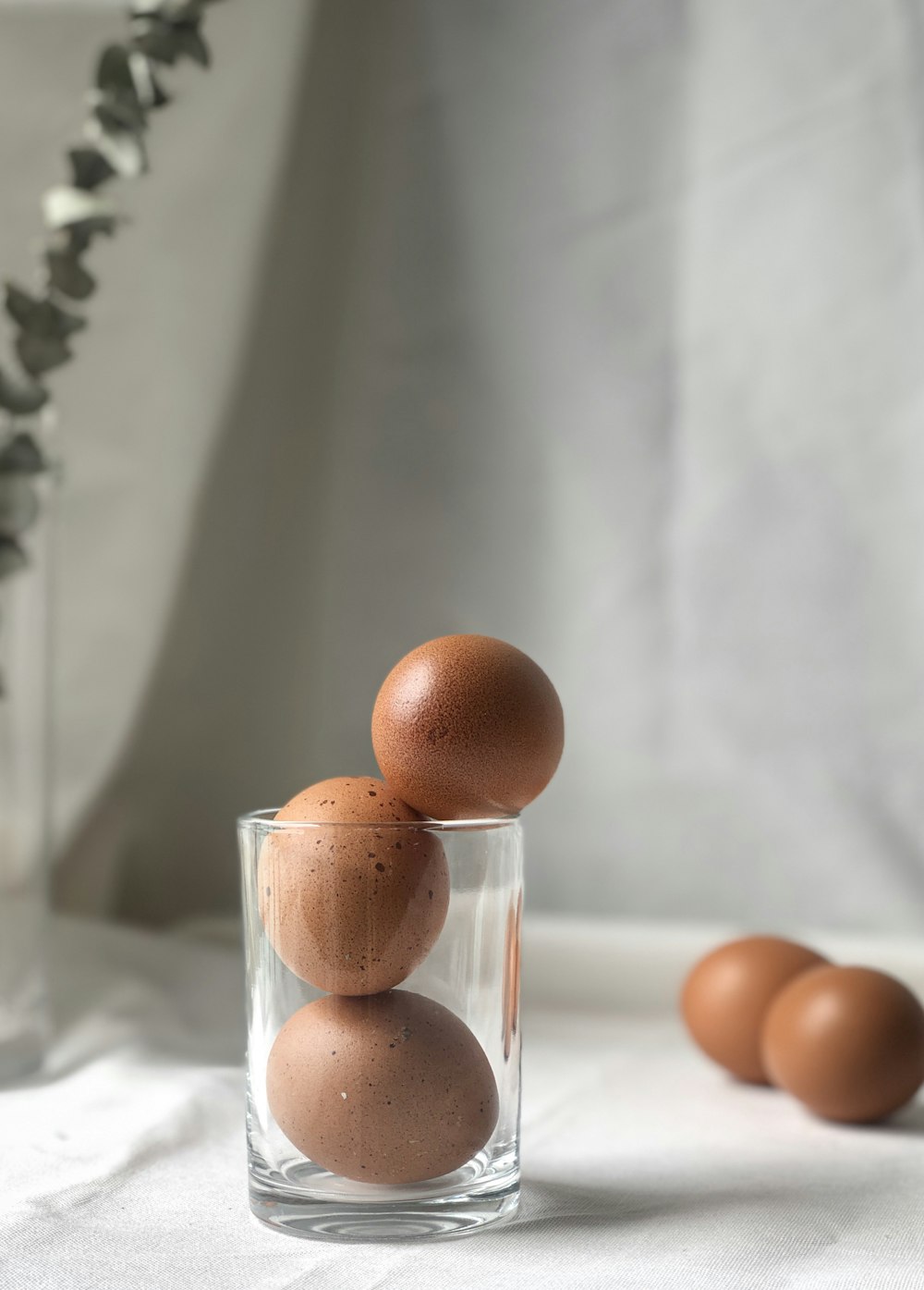 three beige eggs on drinking glass