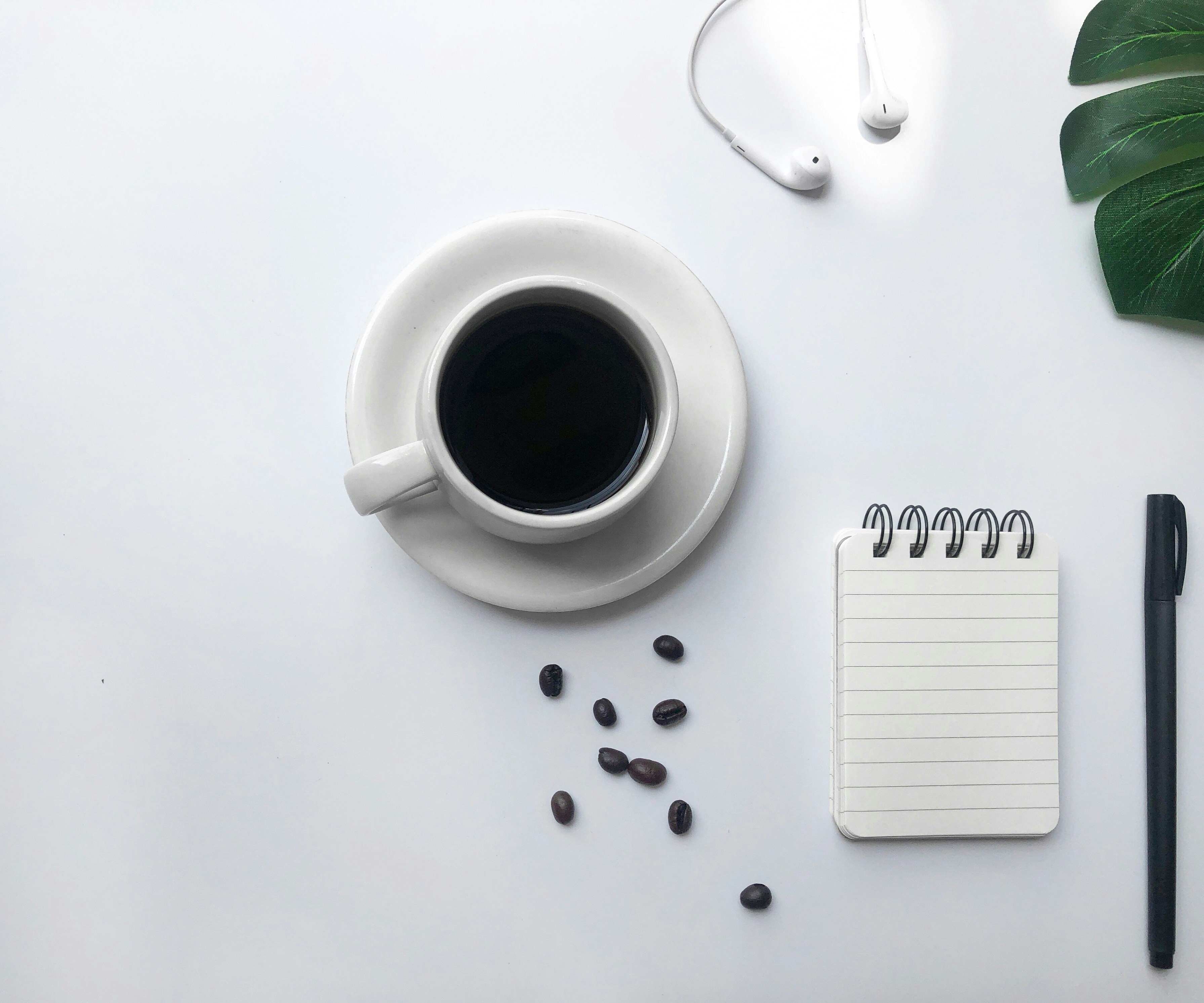 Full coffee mug sitting next to a notebook and pen