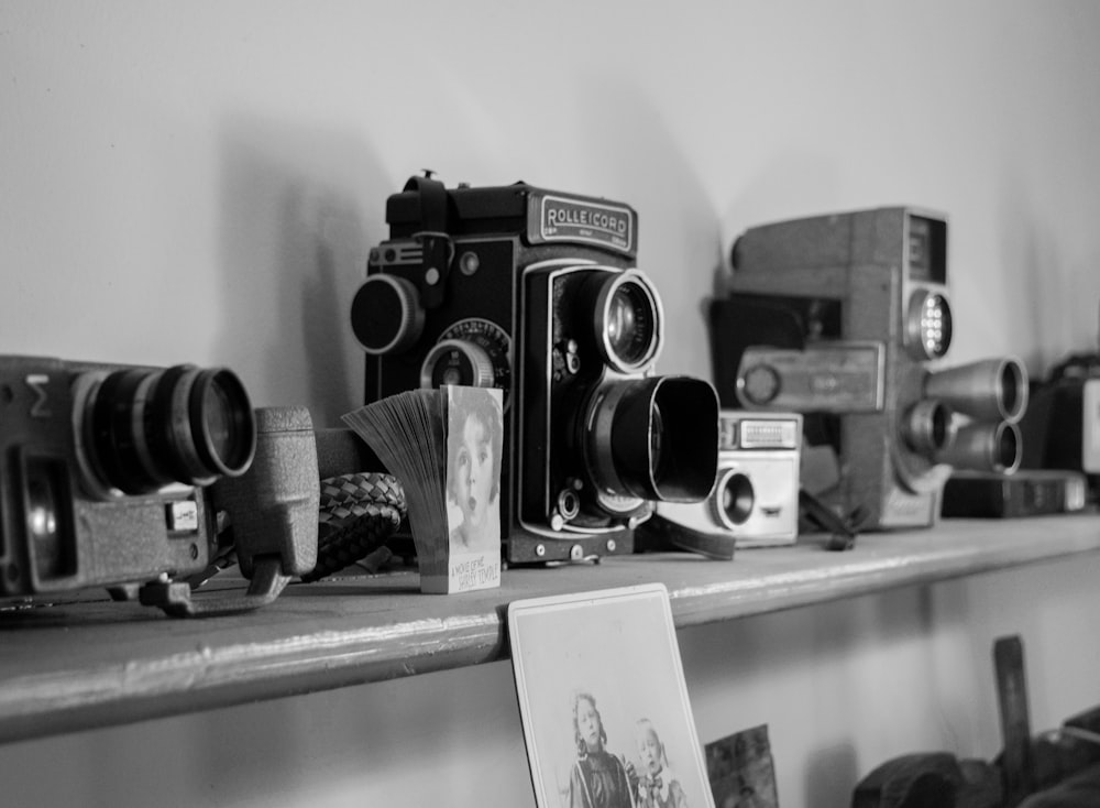 grayscale photo of several cameras on shelf