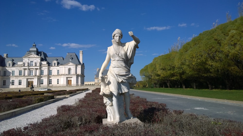 white statue of woman besides road