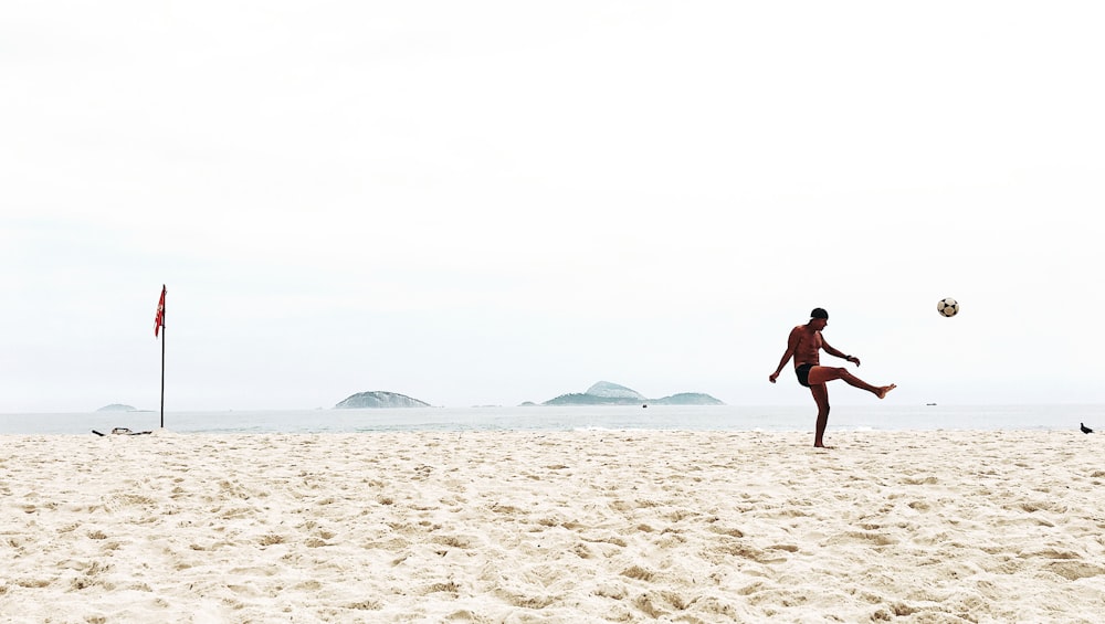 Mann spielt Fußball am Strand
