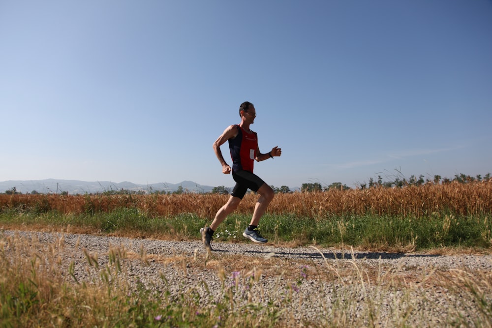 man red and black top running on farm road