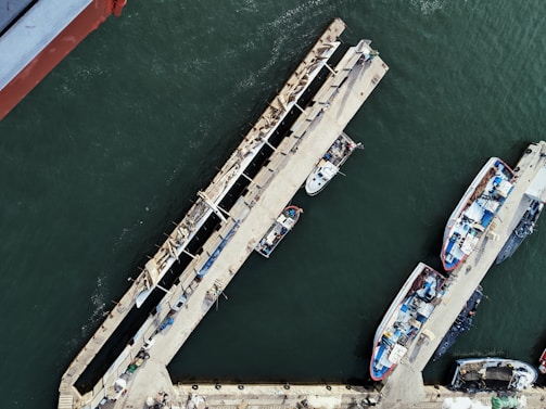 Drone capturing a panoramic view of a harbor with boats lined along the pier.